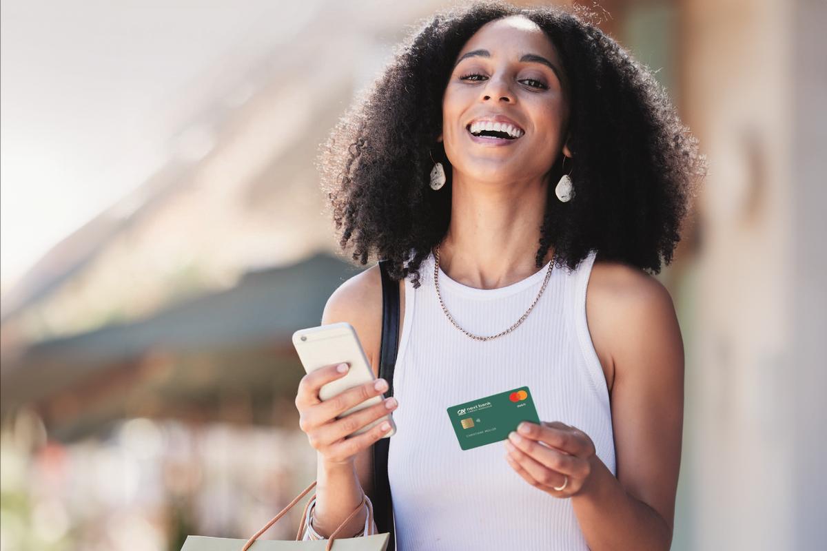 Femme tenant un téléphone et sa carte bancaire CA next bank